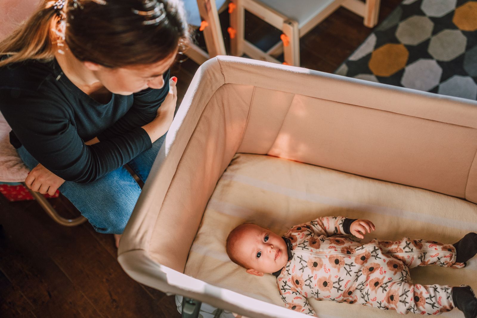 Mother watching over her newborn in a bassinet at home